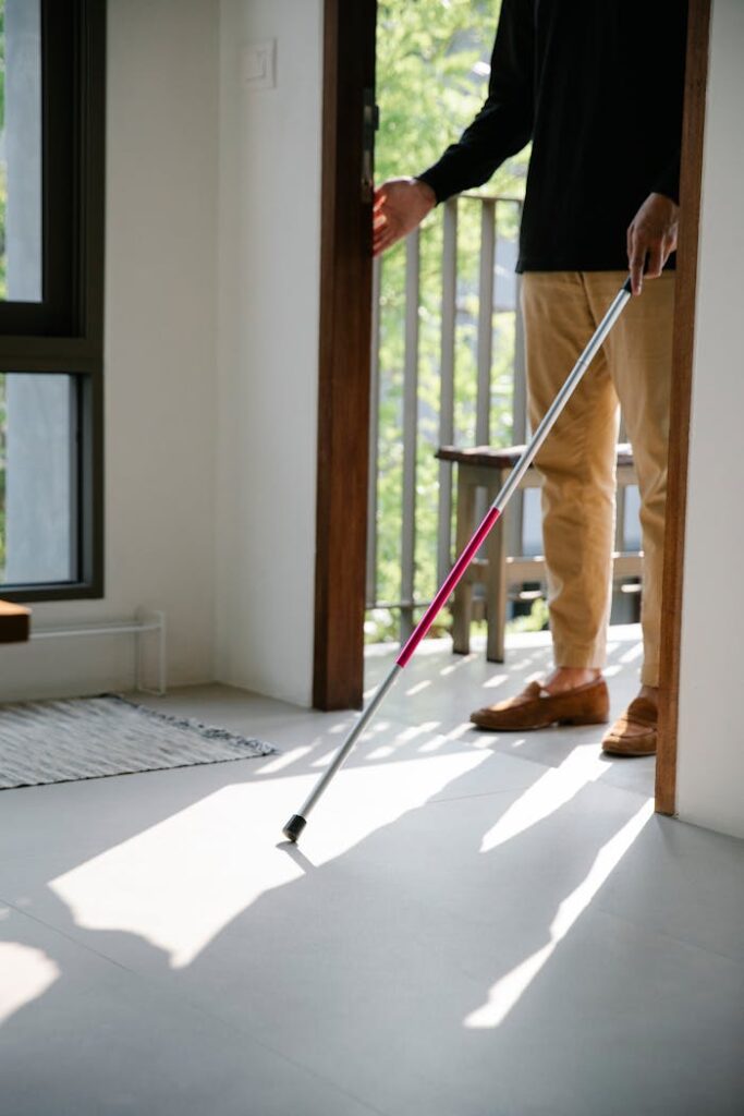 An individual using a white cane for mobility and independence indoors.